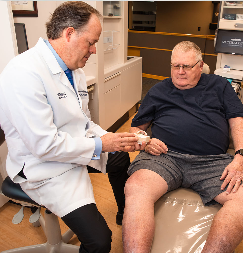 doctor showing patient dental implant model within the dental practice