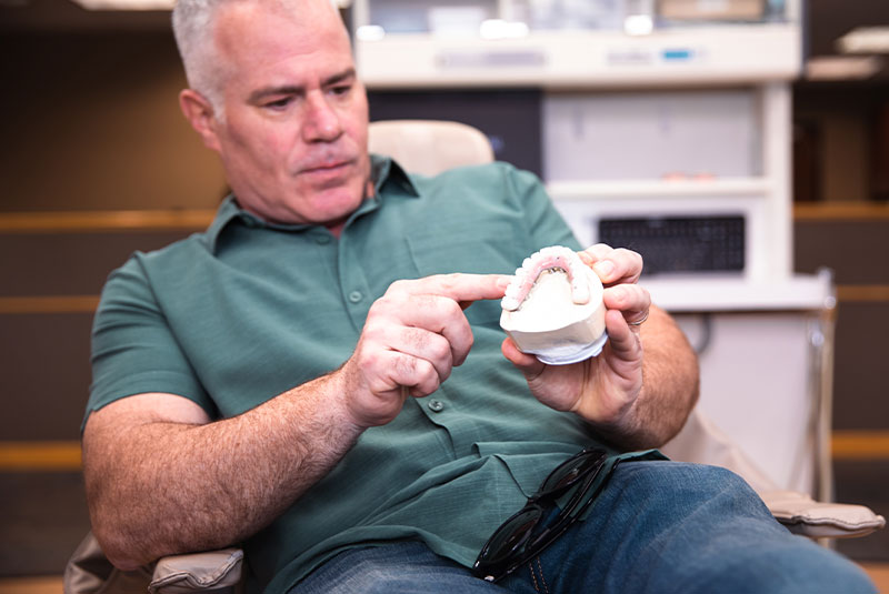 patient examining dental implant model within the dental practice